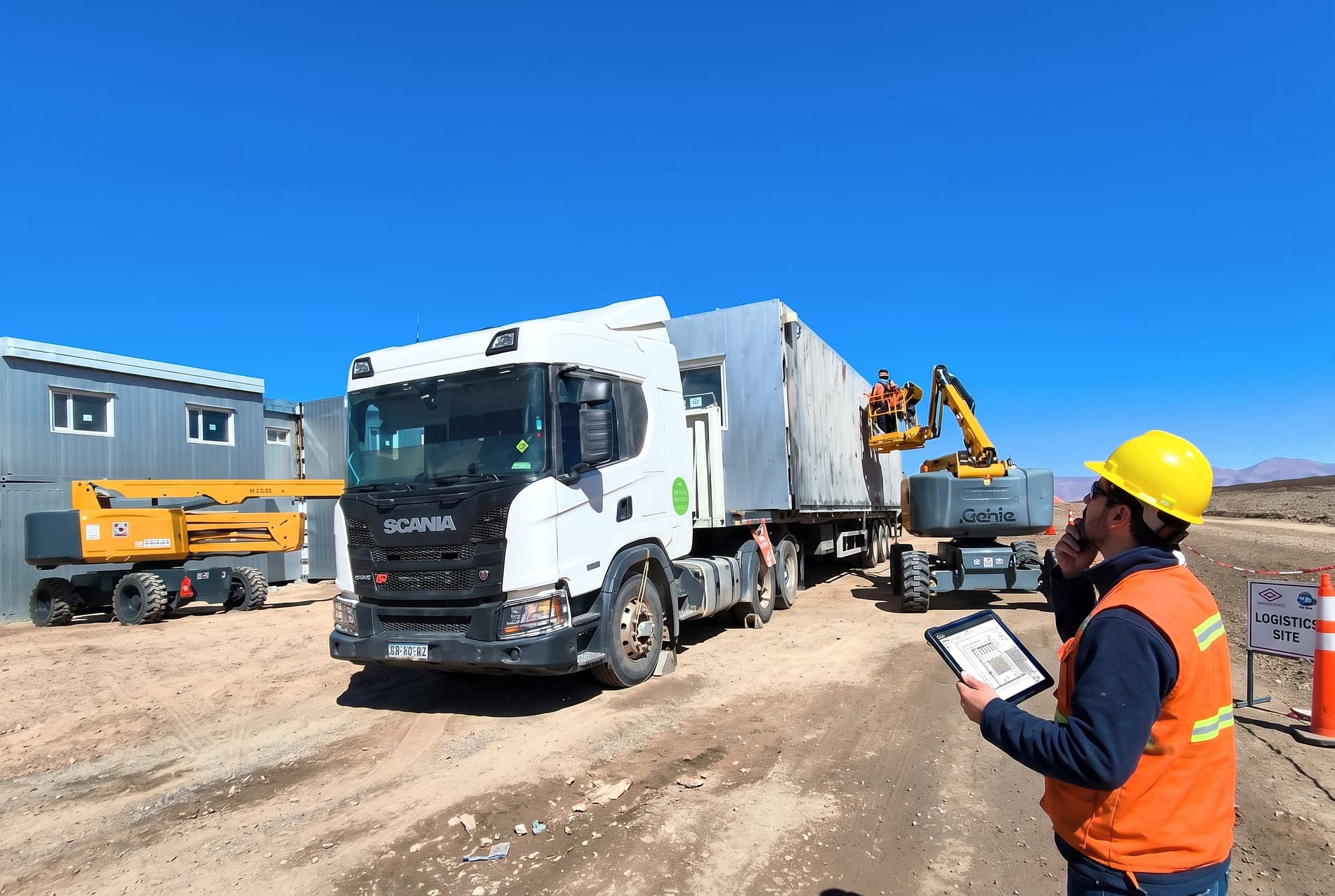 Operario con equipo de protección personal supervisando la descarga de un módulo en obra