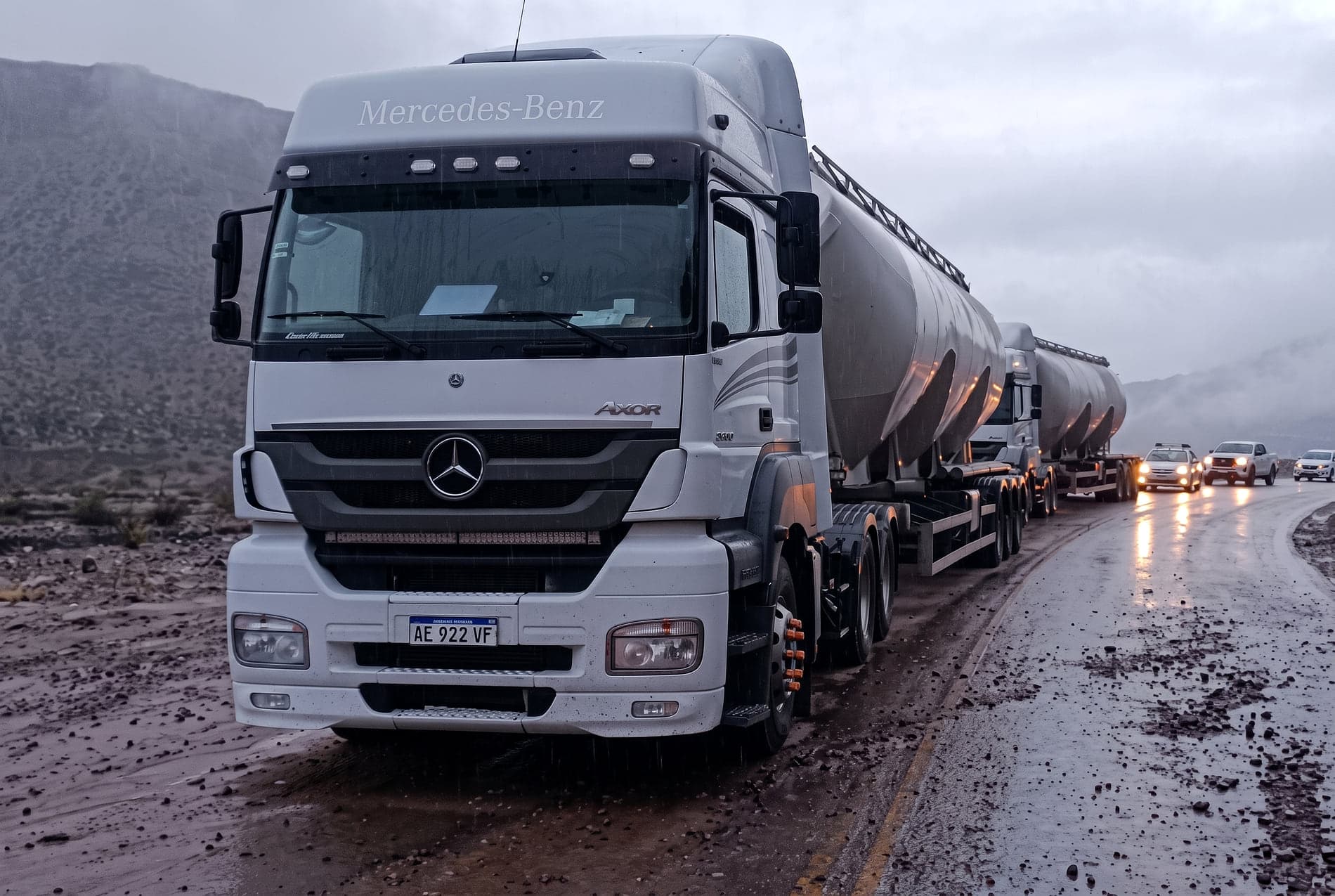 Mercedes-Benz Axor con tolvas circulando bajo lluvia en ruta de montaña