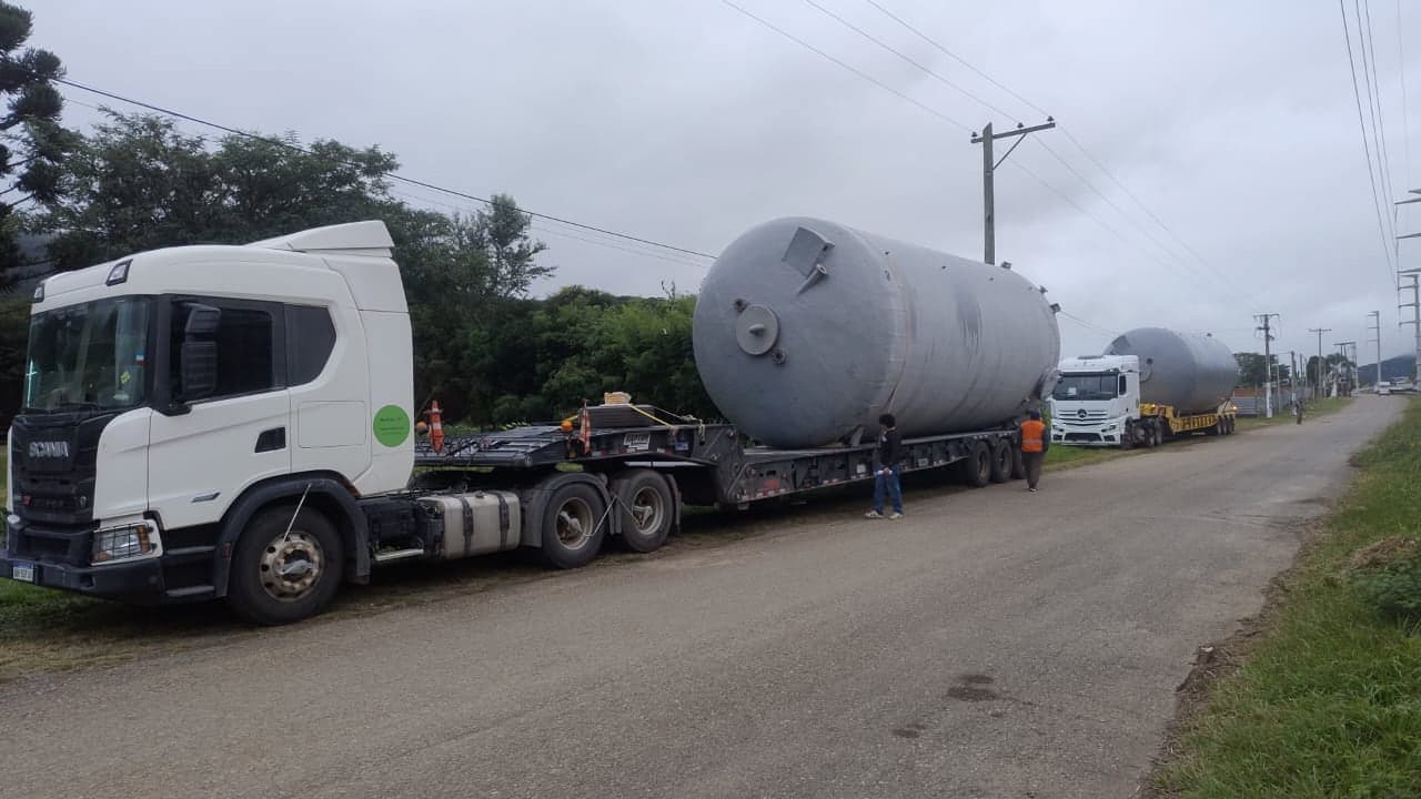 Tractor Scania con tanque gris de gran porte sobre carretón, seguido por otra unidad con carga similar