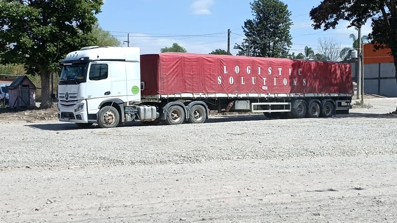 Mercedes-Benz Actros con semirremolque lonado en rojo con la leyenda Logistic Solutions