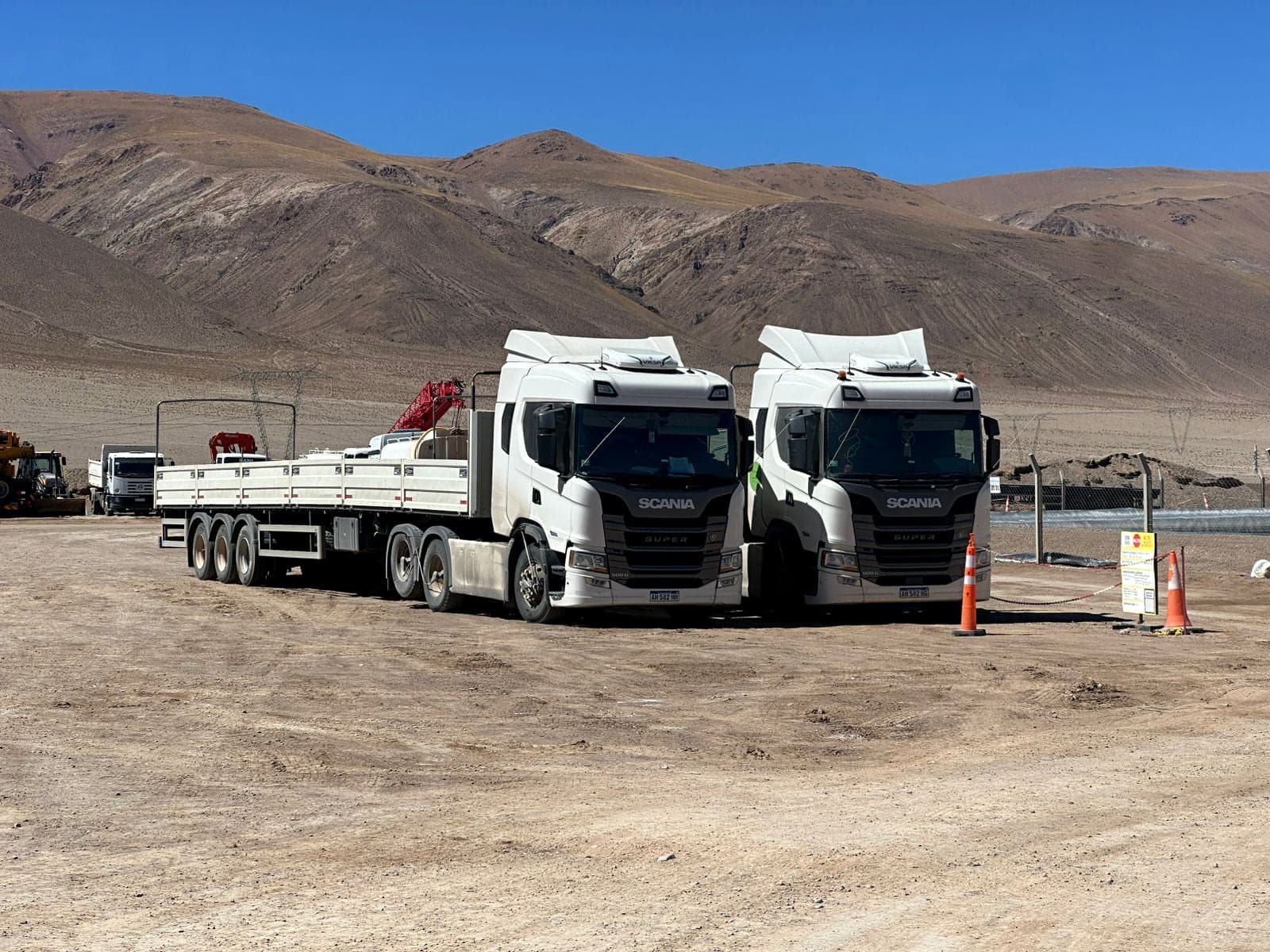 Dos tractores Scania Super con semirremolque en un obrador de la puna, con la cordillera de fondo